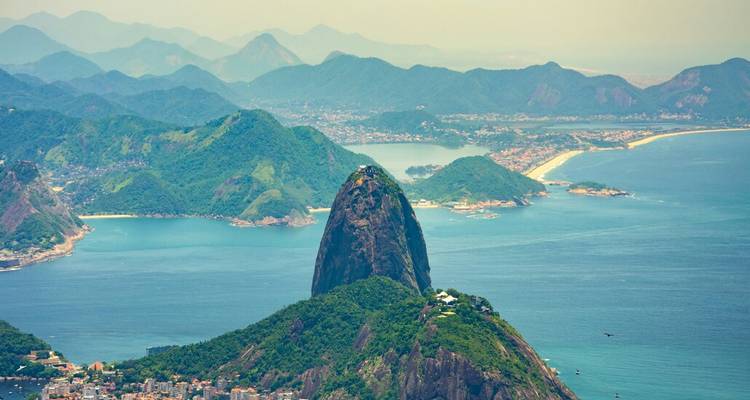 Le Pain de Sucre s'élève au-dessus de la baie de Guanabara avec les plages de la ville et les pics lointains.