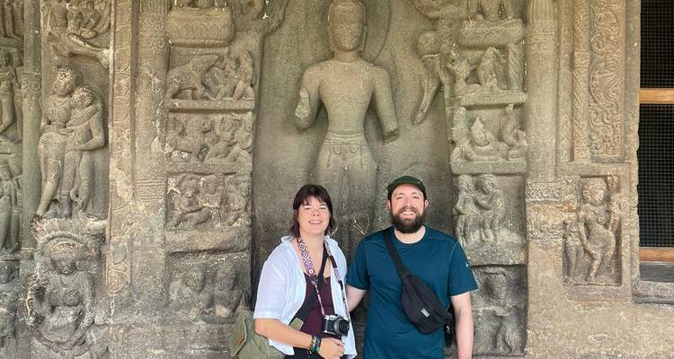 Dos viajeros se encuentran ante grandes relieves de piedra de deidades en el complejo de cuevas de Ajanta.