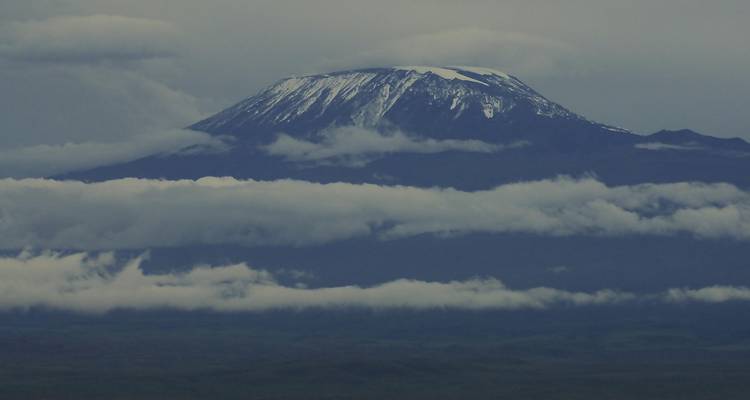 Kilimanjaros Gipfel ragt über Schichten stimmungsvoller Wolken und Nebel hinaus.