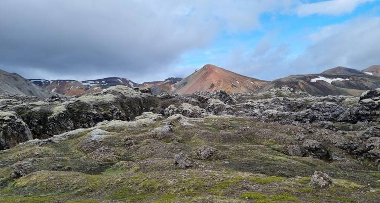 Champ de lave couvert de mousse avec des collines de rhyolite multicolores sous un ciel nuageux dans les hautes terres d'Islande.