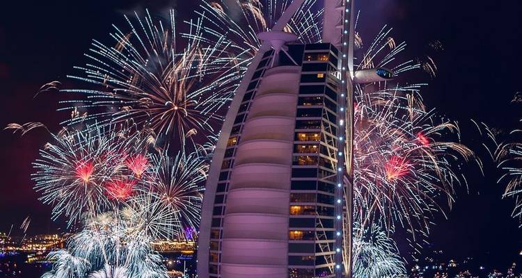 Nachtansicht des Burj Al Arab, beleuchtet mit bunten Feuerwerken, die rund um die Skyline explodieren.