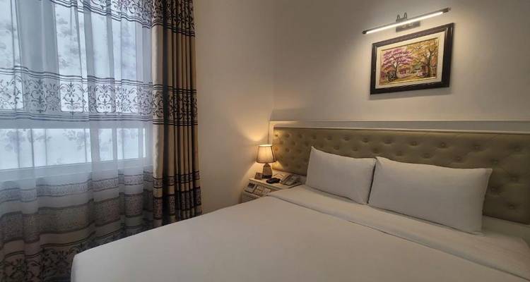 Ordentliches Hotelzimmer mit großem Bett, neutralen Tönen, gerahmten Kunstwerken und weicher Lampenbeleuchtung.