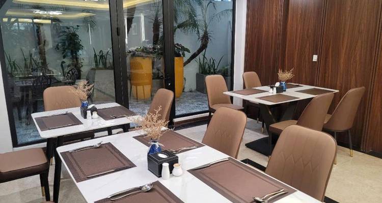 Moderner Hotelspeisenbereich mit ordentlich gedeckten Tischen, braunen Stühlen und großen Glastüren, die sich zu einem kleinen Garten öffnen.