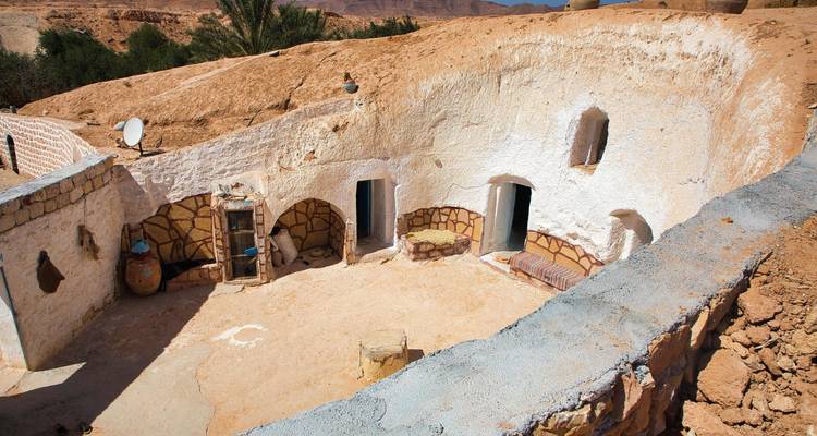 Cour enfoncée d'une maison troglodyte berbère sculptée dans la roche du désert.