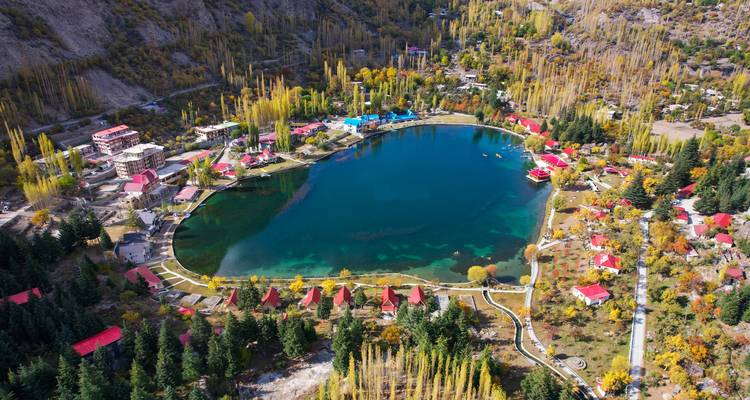Vue aérienne colorée d'un lac en forme de cœur entouré d'arbres d'automne et de chalets au bord du lac.