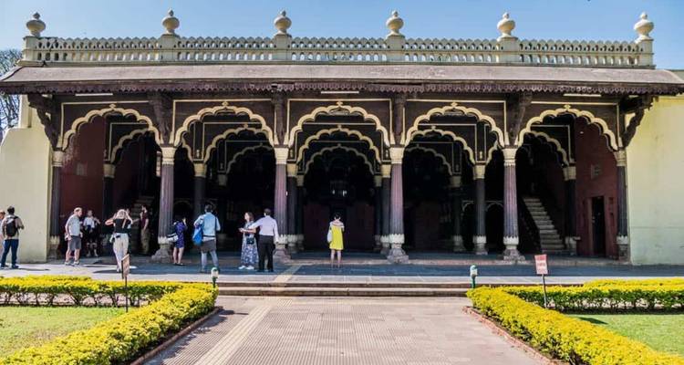 Besucher versammeln sich vor einem historischen Palast mit Bogenfenstern und reicher indo-islamischer Architektur.
