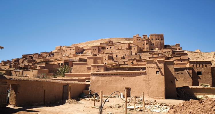 Adobe ksar de Aït Benhaddou elevándose en terrazas contra un cielo desértico despejado.