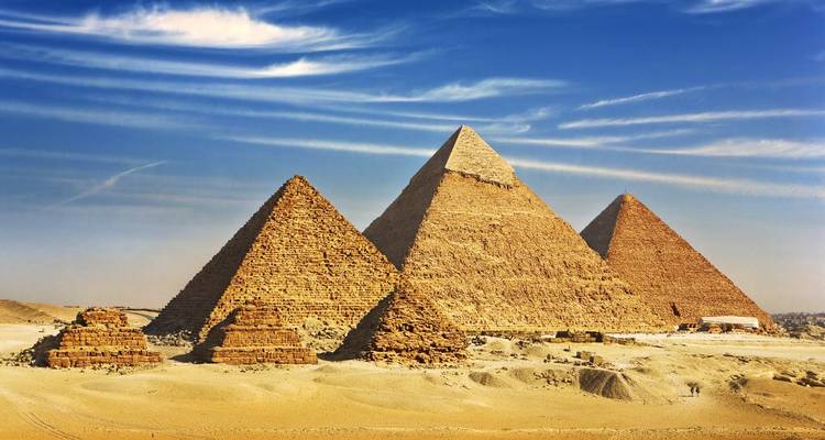 Die drei großen Pyramiden stehen majestätisch auf Wüstensand unter dramatischen gestreiften Wolken.