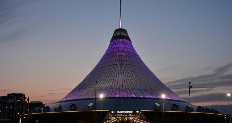 Centre de divertissement Khan Shatyr de forme conique futuriste brillant en violet au crépuscule à Astana.