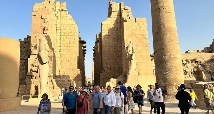 Tourgroep die poseert tussen de massieve zuilen en standbeelden van de Karnak Tempel onder een heldere blauwe hemel