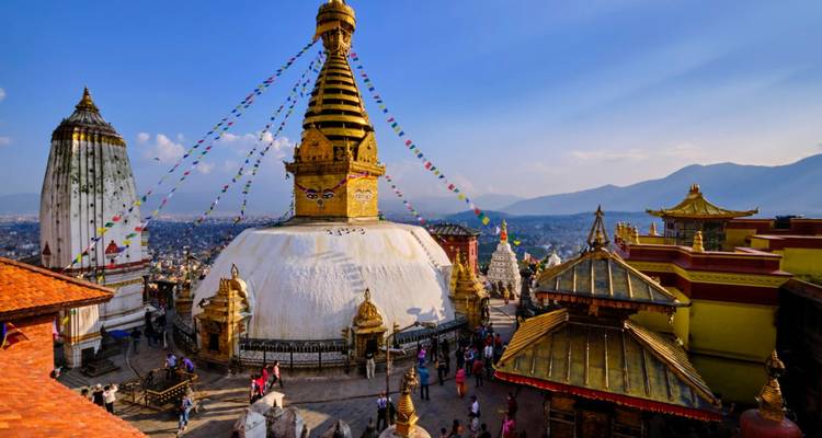 Goldene Stupa von Swayambhunath glänzt unter blauem Himmel, während Gebetsfahnen über Kathmandu flattern.