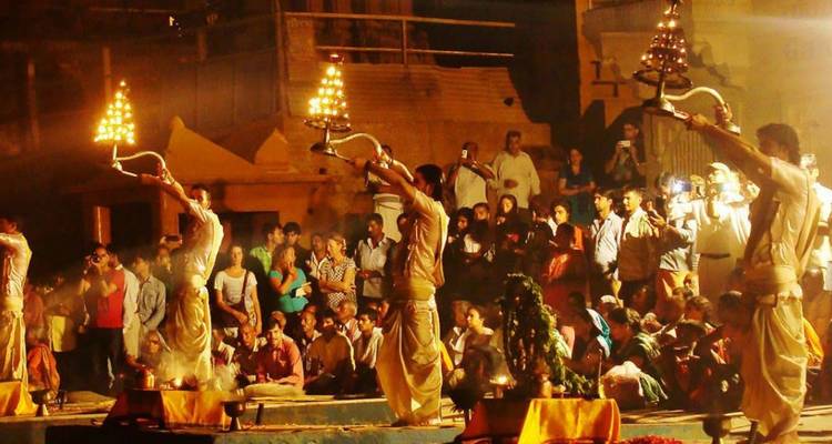 Ceremonia nocturna del Ganga Aarti con sacerdotes alzando lámparas encendidas ante una gran multitud.