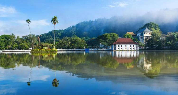 Spiegelglad Kandy Lake weerkaatst omringende tempels en mistige heuvels.
