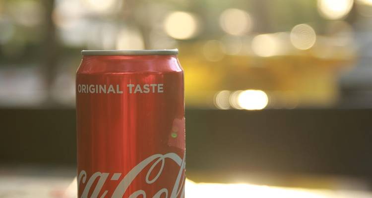 Nahaufnahme einer Coca-Cola-Dose mit verschwommenem sonnigen Hintergrund.