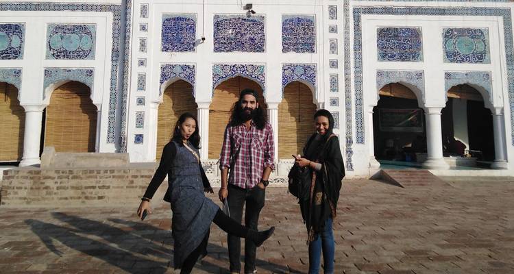 Trois amis posent de manière ludique devant la façade ornée de carreaux bleus d'un bâtiment historique.