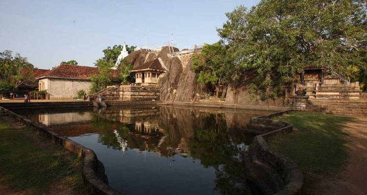 Reflecterende vijver spiegelt in rots gehouwen tempelgebouwen en weelderige bomen in Anuradhapura.