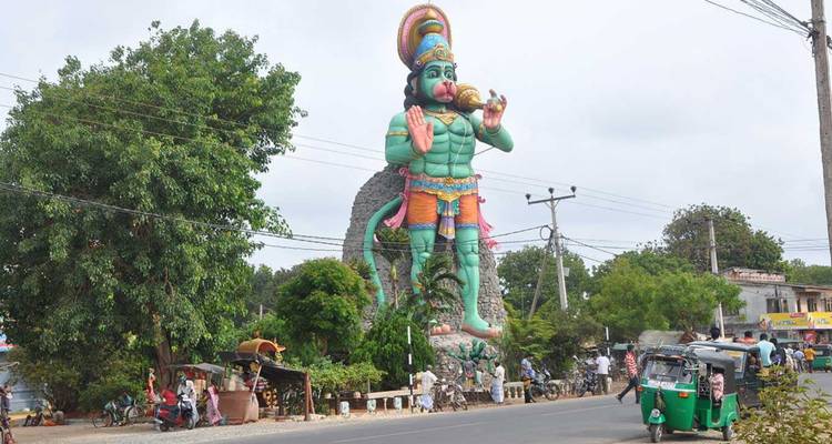 Gigantisch kleurrijk Hanuman-standbeeld torent uit boven winkels langs de weg en tuk-tuks in Sri Lanka.