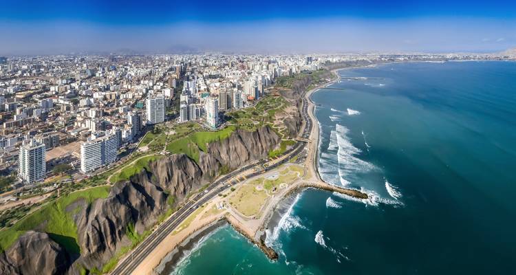Aerial panorama of Lima's dramatic cliff-top Miraflores district and Pacific coastline with rolling surf.