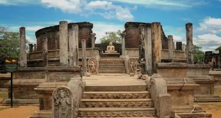 Stenen zuilen Vatadage met zittend Boeddhabeeld in Polonnaruwa onder blauwe hemel
