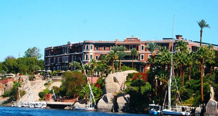 Elegantes Riverside-Hotel im Kolonialstil, umgeben von üppigen Palmen und vor Anker liegenden Segelbooten am Nil