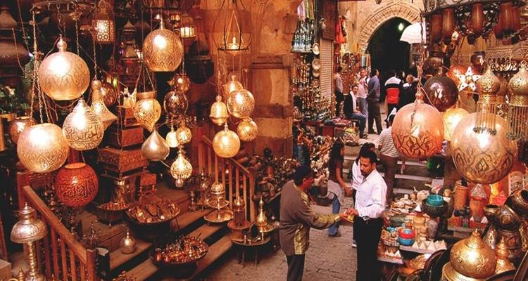 Bullicioso bazar de Khan el-Khalili lleno de linternas de latón colgantes y compradores negociando en callejones estrechos.