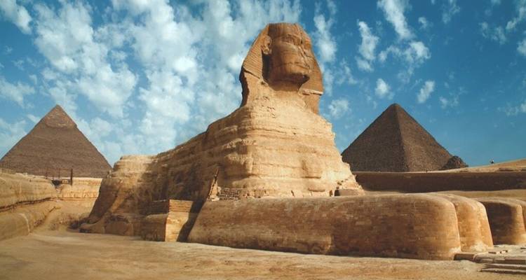 Klassischer Blickwinkel der Sphinx vor den Pyramiden unter einem gemusterten Wolkenhimmel.