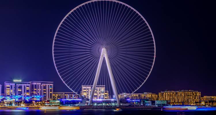 Vue nocturne de la grande roue Ain Dubai qui brille au-dessus de l'horizon de la marina.