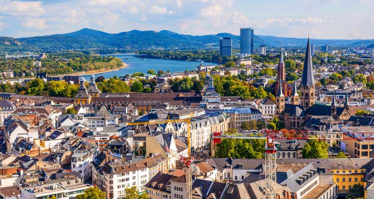 Une vue panoramique de Bonn, le Rhin s'étendant devant la ville avec des collines lointaines à l'horizon.
