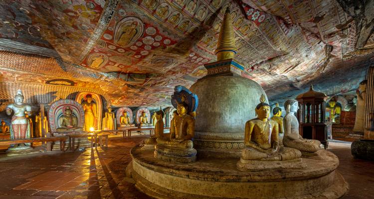 Intérieur du temple rupestre de Dambulla richement décoré de statues de Bouddha et de peintures murales vives au plafond.