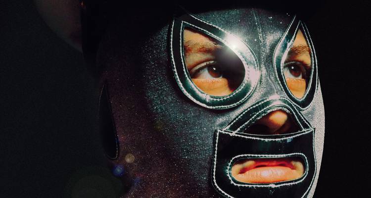 Dramatisch portret van een persoon die een sprankelend zwart lucha libre masker draagt tegen een donkere achtergrond.