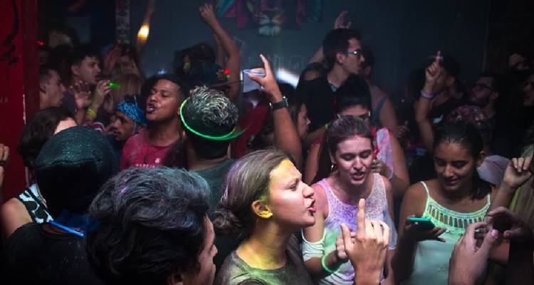 Levendige nachtclubscène met dansende menigte onder kleurrijke lichten en glow accessoires.