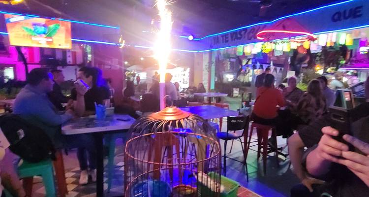 Levendig bar-interieur met neonverlichting, gasten, en vuurwerk-achtige sterretjes boven de tafels.