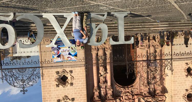 Reisender steht neben übergroßen skulpturalen Buchstaben vor einer verzierten Steinkirchenfassade.