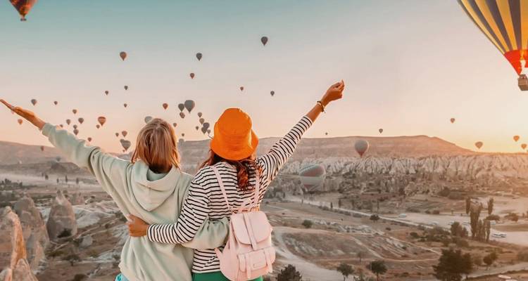 Imagen duplicada: mujeres celebrando el amanecer en globo aerostático sobre el paisaje de Capadocia.
