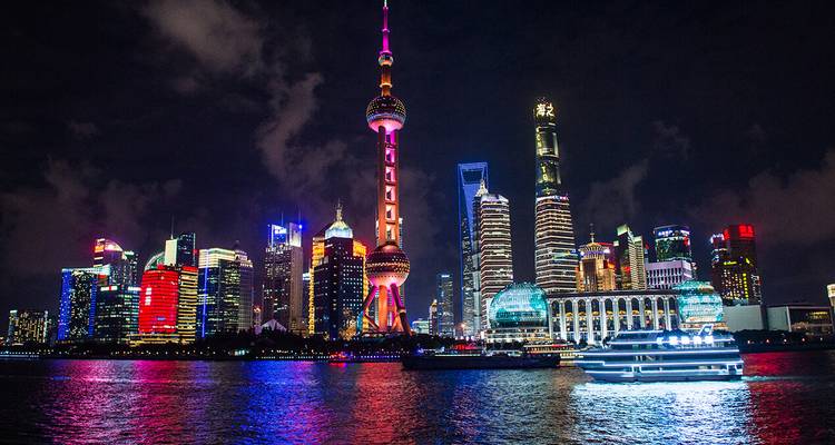 Lebendige nächtliche Skyline von Shanghais Pudong mit hell erleuchteten Wolkenkratzern, die sich im Huangpu-Fluss spiegeln.