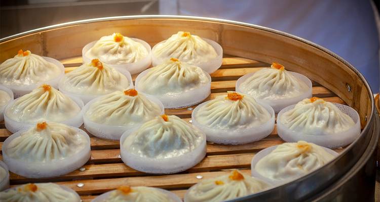 Dampfkorb gefüllt mit ordentlich arrangierten Xiaolongbao-Teigtaschen, bereit zum Servieren.