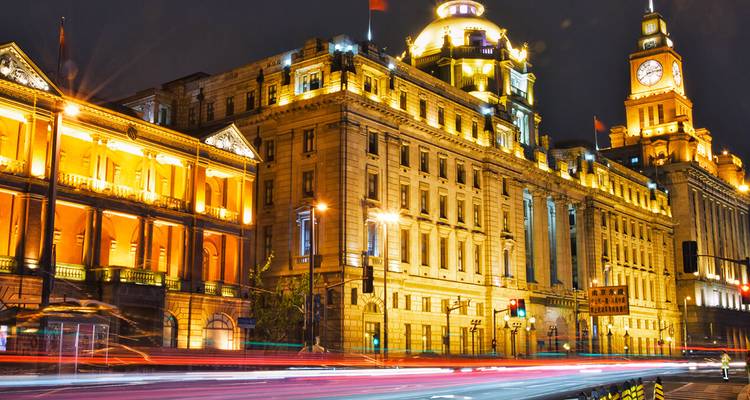Historische beleuchtete Gebäude an der Bund in Shanghai mit Lichtspuren von Verkehrsampeln bei Nacht.