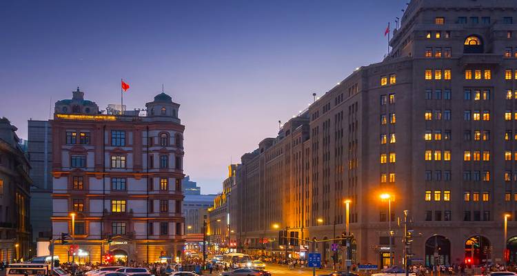 Abendliche Straßenszene an der Bund mit leuchtenden Straßenlaternen und flaggenbekrönten historischen Gebäuden.