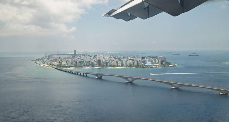 Luchtfoto van Male Island met lange brug en vliegtuigvleugel in beeld boven turkooisblauwe zee