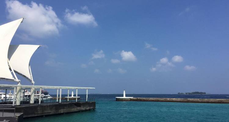 Marinapier met wit zeilachtig afdak naast helder turquoise havenwaters