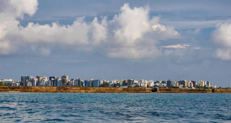 Skyline van Male gezien over kalm blauw water onder verspreide wolken