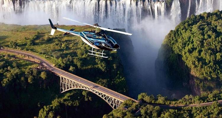 Un hélicoptère survolant les chutes Victoria et le pont emblématique qui enjambe les gorges