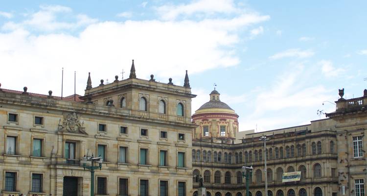 Historische koloniale gebouwen rondom Plaza Bolívar met blauwe lucht boven je hoofd.