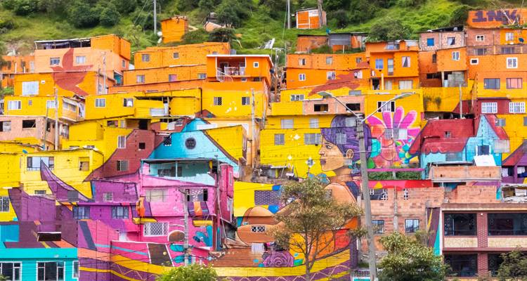 Kleurrijke street art-bedekte huizen gestapeld op een heuvelzijde van Medellin die een levendige mozaïek creëren.