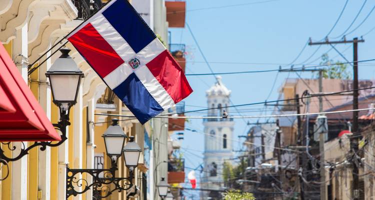 De vlag van de Dominicaanse Republiek hangt langs een kleurrijke koloniale straat in het historische centrum van Santo Domingo.