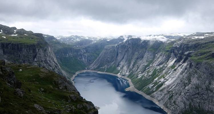 Fjord spectaculaire avec des falaises escarpées surplombant un lac étroit sous un ciel nuageux et menaçant