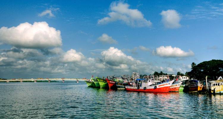 Kleurrijke vissersboten afgemeerd op rustige backwaters onder wollige wolken in Kerala
