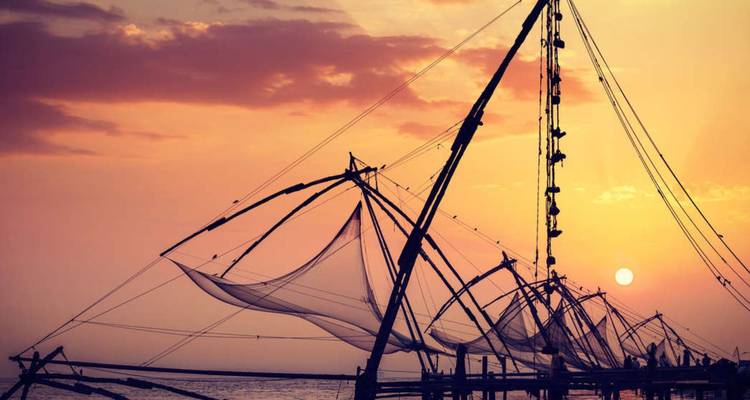 Gesilhouetteerde Chinese visnetten boven de Arabische Zee bij zonsondergang
