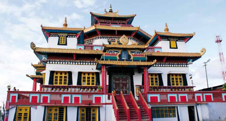 Colorful Buddhist monastery with ornate golden roofs against a blue sky.