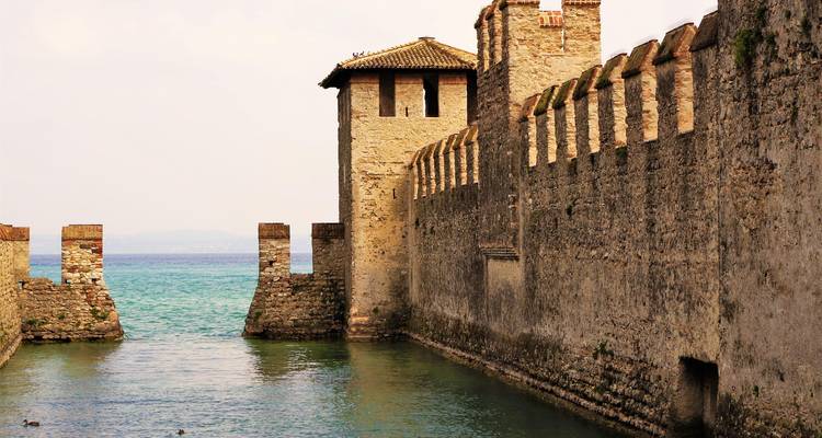 Mittelalterliche Steinmauern und Turm der Scaligerburg, die sich in die türkisfarbenen Gewässer des Gardasees erstrecken